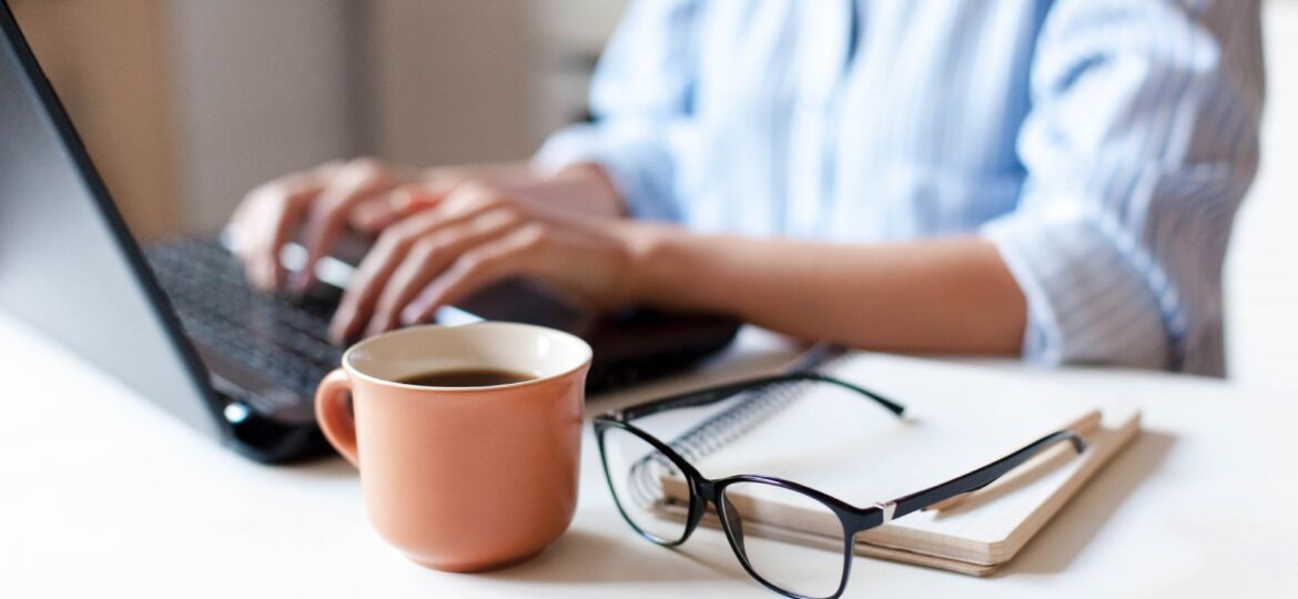 Remote working from home. Freelancer workplace in kitchen with laptop, cup of coffee